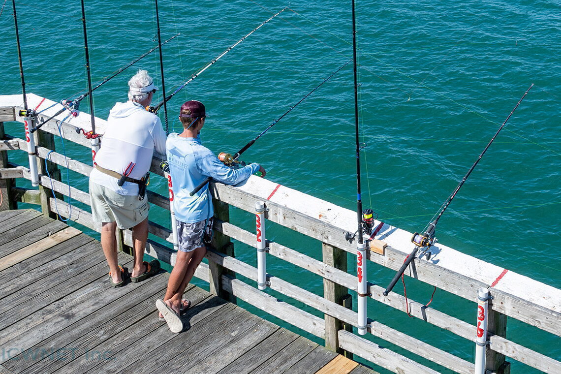 A Cart Full of Fishing Gear is Located on a Pier with a Beach in
